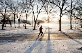 A man is running on a road through a winter sunrise