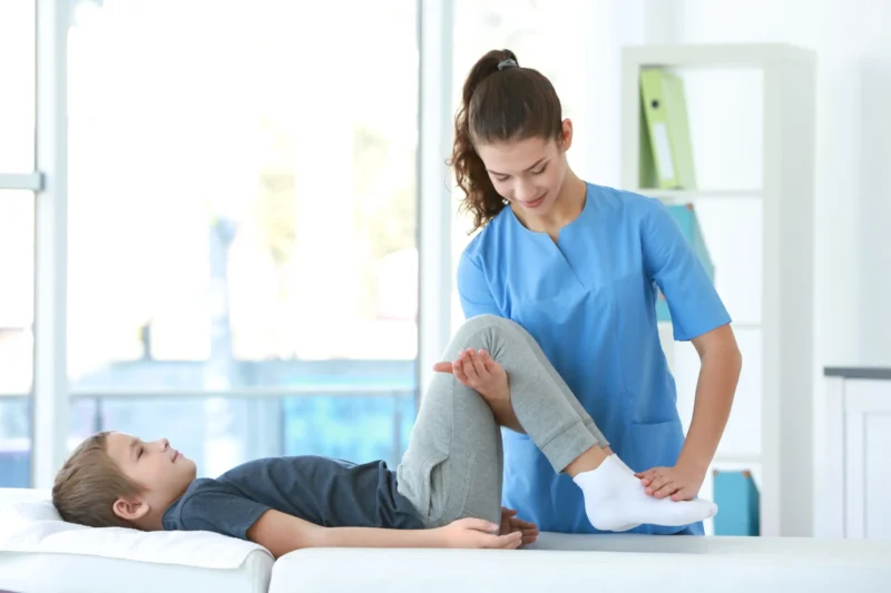 a young child lies on the bench of a young brown-haired female therapist.