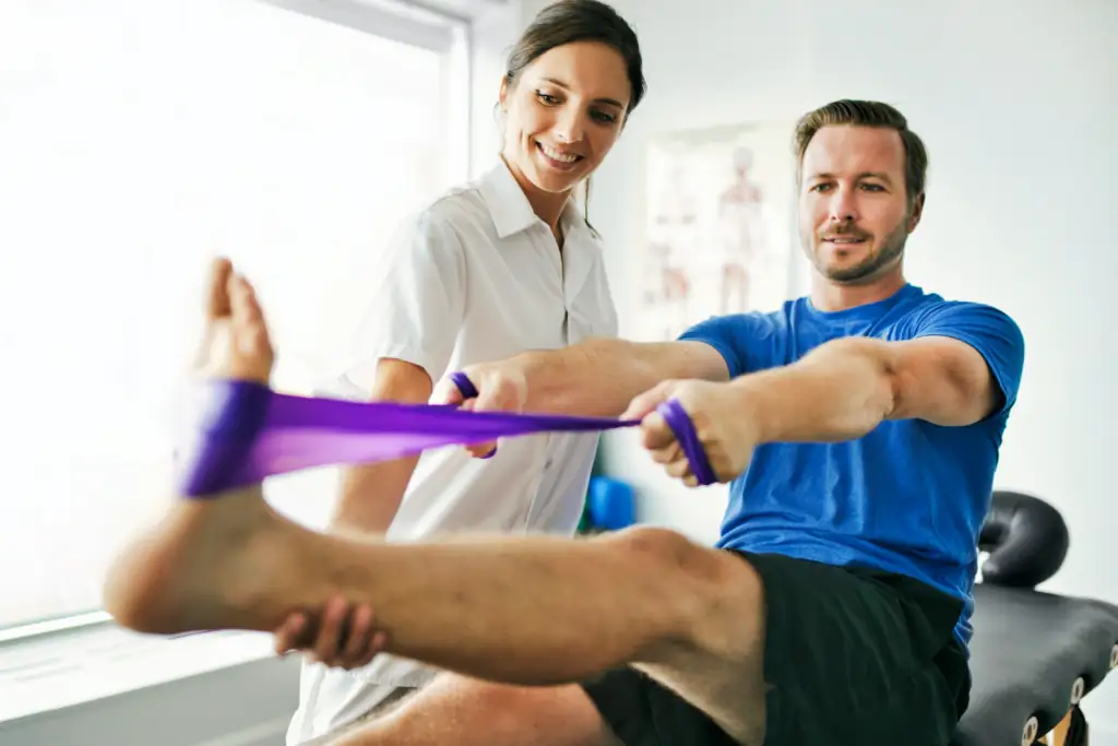 a middle-aged man with a short-trimmed beard is doing resistance therapy with a brown-haired female therapist