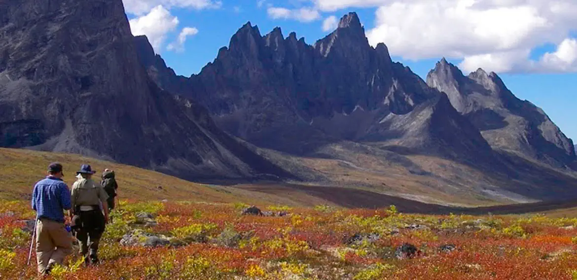 a group of hikers stand in a mountain valley with autumn colours